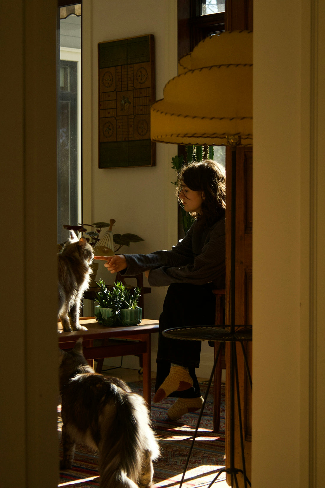 A woman sitting at a table with a cat and dog